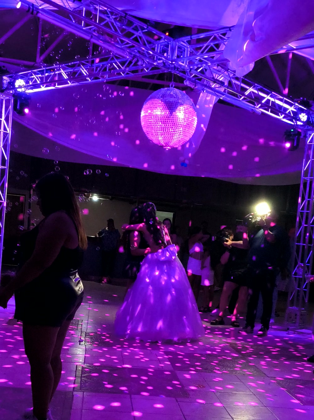 Bola de espejos, burbujas y estructuras de luz sobre la pista en una fiesta de 15